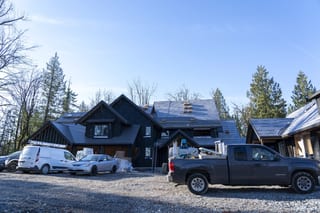 Musket Grey Interlock Slate aluminum roof being installed on a modern home with a metal roof in a forest setting, Abbotsford, British Columbia