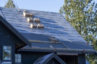 Musket Grey Interlock Slate aluminum roof being installed on a modern house with a metal roof under construction in a, Abbotsford, British Columbia