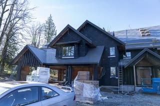 Musket Grey Interlock Slate aluminum roof being installed on a grey two-storey home with dormers under construction, Abbotsford, British Columbia