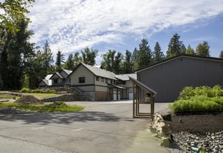 Musket Grey Interlock Slate aluminum roof on a two-storey home with dormers among tall conifers, Abbotsford, British Columbia