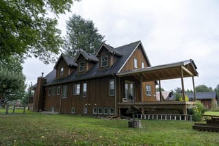 Hunter Green Interlock Slate aluminum roof on a brown two-storey home with dormers among tall trees, Langley, British Columbia