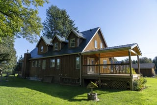 Hunter Green Interlock Slate aluminum roof on a brown single-storey home with a covered porch in a forest, Langley, British Columbia