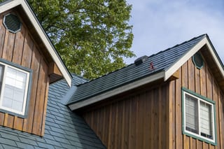 Hunter Green Interlock Slate aluminum roof on a brown house with a green roof among tall trees, Langley, British Columbia