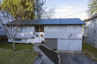 Deep Charcoal Interlock Slate aluminum roof on a grey home with dormers among tall pines, Mission, British Columbia