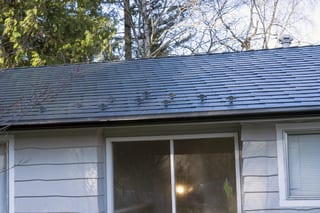 Deep Charcoal Interlock Slate aluminum roof on a white single-storey home with a gable in a forested area, Mission, British Columbia