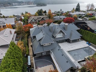 Deep Charcoal Interlock Slate aluminum roof on a modern home with a metal roof among tall trees on, North Vancouver, British Columbia