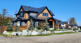 Two-storey Craftsman home in Tsawwassen BC with a complex steep Interlock aluminum slate roof in deep charcoal, boulder-lined landscaping, and cedar accents.