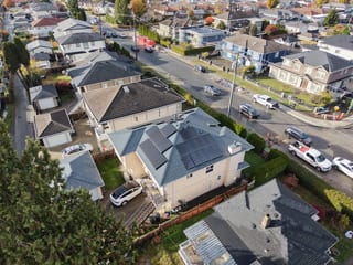 Deep Charcoal Interlock Slate aluminum roof on a beige single-family home with a metal roof among houses, Burnaby, British Columbia