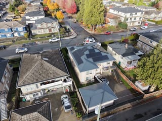 Deep Charcoal Interlock Slate aluminum roof on a white two-storey home with dormers among tall trees, Burnaby, British Columbia