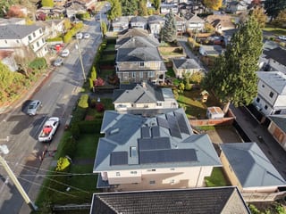 Deep Charcoal Interlock Slate aluminum roof on a beige single-family home with dormers among tall trees, Burnaby, British Columbia