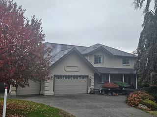 Tudor Brown Interlock Shake aluminum roof on a beige two-storey home with a gable and dormer in autumn, Surrey, British Columbia