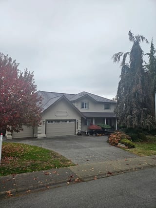 Tudor Brown Interlock Shake aluminum roof on a grey two-storey Tudor home with dormers and a Tudor Brown, Surrey, British Columbia