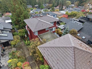 Colonial Brown Interlock Shake aluminum roof on a red Colonial two-storey home with dormers among tall, North Vancouver, British Columbia