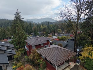 Colonial Brown Interlock Shake aluminum roof on a red two-storey home with a brown metal roof among tall, North Vancouver, British Columbia