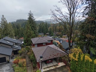 Colonial Brown Interlock Shake aluminum roof on a red two-storey home with dormers among tall trees, North Vancouver, British Columbia