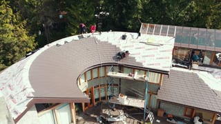 Completed Interlock aluminum Tudor Brown slate metal roof on a West Vancouver, BC home, showing the profile's fit on the home's rounded roofline.