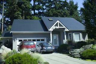 Black Interlock Slate aluminum roof on a grey single-family home with a metal roof among trees, Victoria, British Columbia