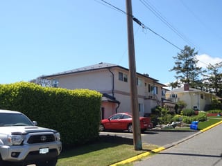 Black Interlock Slate aluminum roof on a beige two-storey home with a metal roof under, Victoria, British Columbia