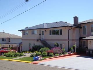 Black Interlock Slate aluminum roof on a beige two-storey home with a metal roof and chimney in a, Victoria, British Columbia
