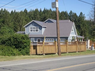 Weathered Interlock Slate aluminum roof on a two-storey home with a grey metal roof in a forested area, Duncan, British Columbia