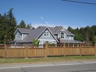 Weathered Interlock Slate aluminum roof on a grey two-storey home with dormers in a forested suburban, Duncan, British Columbia