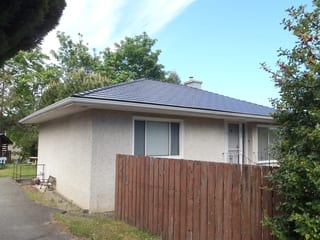 Black Interlock Cedar Shingle aluminum roof on a beige one-storey home with a small chimney and a fence, Chemainus, British Columbia