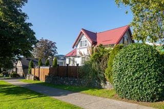 Tile Red Interlock Slate aluminum roof on a red metal roofed house with dormers on a suburban street, Victoria, British Columbia