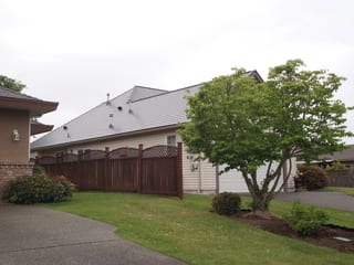 Deep Charcoal Interlock Slate aluminum roof on a white home with a metal roof in a suburban neighbourhood, Qualicum Beach, British Columbia