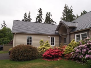 Deep Charcoal Interlock Slate aluminum roof on a tan house with a grey metal roof in a coastal urban, Qualicum Beach, British Columbia