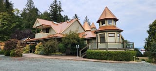 Copper Penny Interlock Slate aluminum roof on a beige single-family home with a metal roof in a forested, Ladysmith, British Columbia