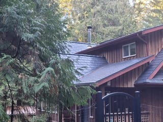 Deep Charcoal Interlock Slate aluminum roof on a brown single-storey cottage with a metal roof and dormer, Gabriola Island, British Columbia