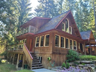 Deep Charcoal Interlock Slate aluminum roof on a brown chalet with a metal roof in a forested lakeside, Gabriola Island, British Columbia