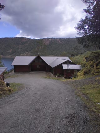 Deep Charcoal Interlock Slate aluminum roof on a brown home with a metal roof among green trees on a hill, Juan de Fuca, British Columbia