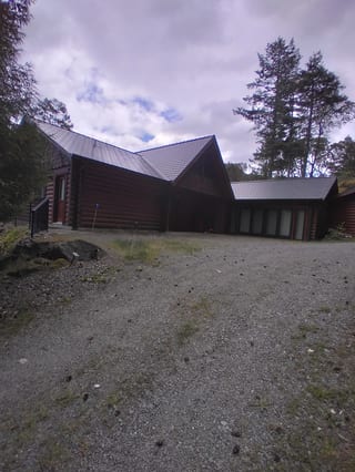 Deep Charcoal Interlock Slate aluminum roof on a brown home with a gable roof among tall evergreens, Juan de Fuca, British Columbia