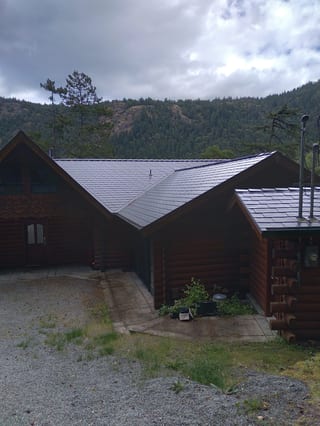 Deep Charcoal Interlock Slate aluminum roof on a dark wood chalet in the forest with a metal roof, Juan de Fuca, British Columbia