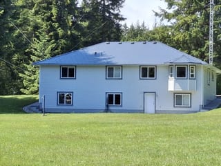 Deep Charcoal Interlock Slate aluminum roof on a white modern home with a metal roof in a forested rural, Courtenay, British Columbia