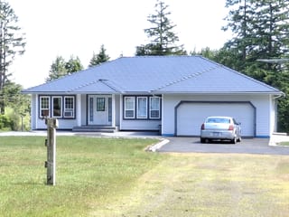 Deep Charcoal Interlock Slate aluminum roof on a light-colored home with a metal roof in a coastal forest, Courtenay, British Columbia