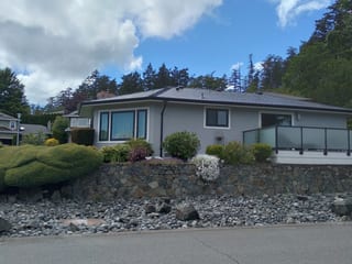 Black Interlock Slate aluminum roof on a grey two-storey home with dormers on a lakeside street, Victoria, British Columbia