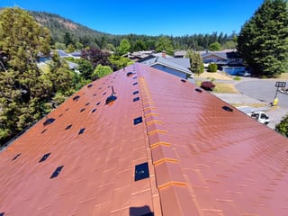 Copper Penny Interlock Slate aluminum roof on a two-storey home with dormers in a forested area, Victoria, British Columbia