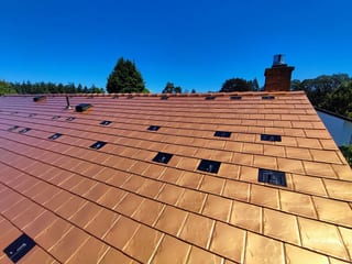 Copper Penny Interlock Slate aluminum roof on a brown two-storey home with dormers in a suburban, Victoria, British Columbia