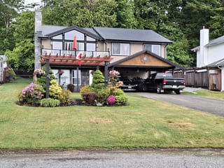 Black Interlock Slate aluminum roof on a two-storey home with a brown metal roof and brown trim, Chemainus, British Columbia