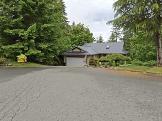 Black Interlock Slate aluminum roof on a metal roofed home among tall trees in a rural setting, Duncan, British Columbia
