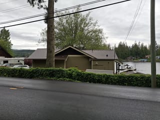 Colonial Brown Interlock Slate aluminum roof on a colonial home with a brown roof among tall trees and water, Shawnigan Lake, British Columbia