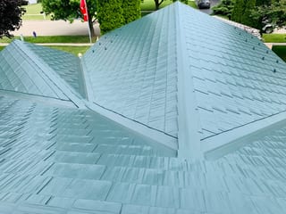 Hunter Green Interlock Shingle aluminum roof on a green metal roof on a two-storey home among tall pines in, Winnebago, Illinois