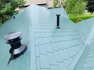 Hunter Green Interlock Shingle aluminum roof on a two-storey home with dormers among tall trees, Winnebago, Illinois