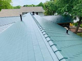 Hunter Green Interlock Shingle aluminum roof on a two-storey home with hunter green metal roof in a forest, Winnebago, Illinois