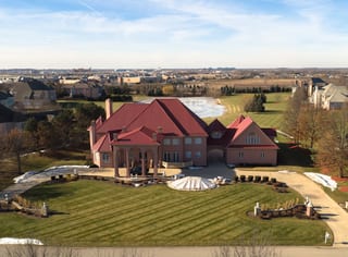 Tile Red Interlock Tile aluminum roof on a red roof on a two-storey home in a grassy suburban setting, South Barrington, Illinois