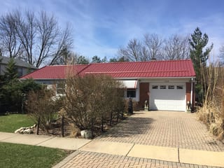 Tile Red Interlock Tile aluminum roof on a red roofed home with a brick driveway in a suburban, Schaumburg, Illinois