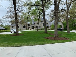 Musket Grey Interlock Slate aluminum roof on a beige colonial home with dormers among tall trees, Long Grove, Illinois