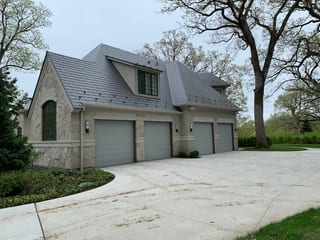 Musket Grey Interlock Slate aluminum roof on a beige two-storey home with dormers in a wooded suburban, Long Grove, Illinois